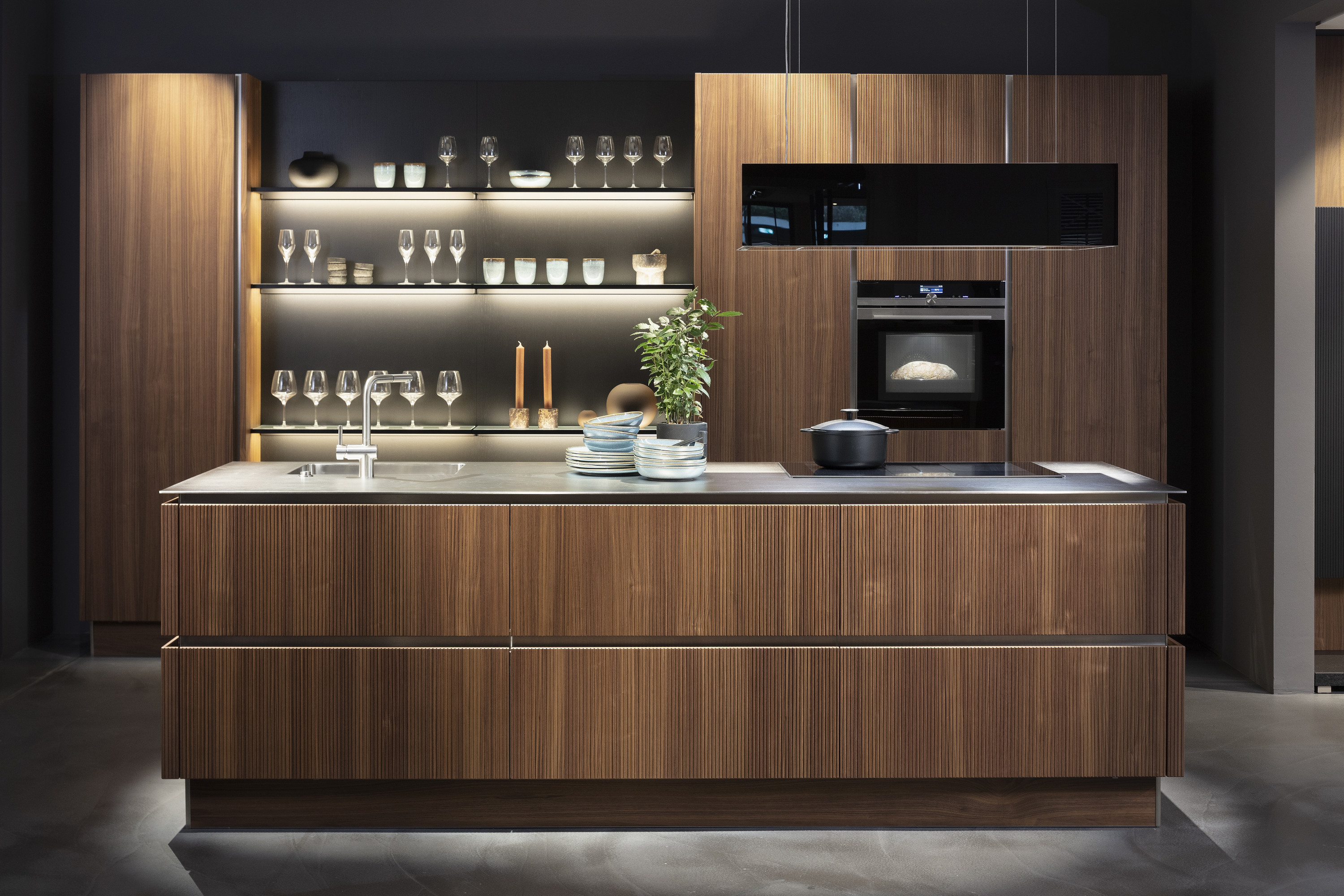 Moderne Küche mit Holzfronten, Insel, offenen Regalen und eingebautem Backofen.