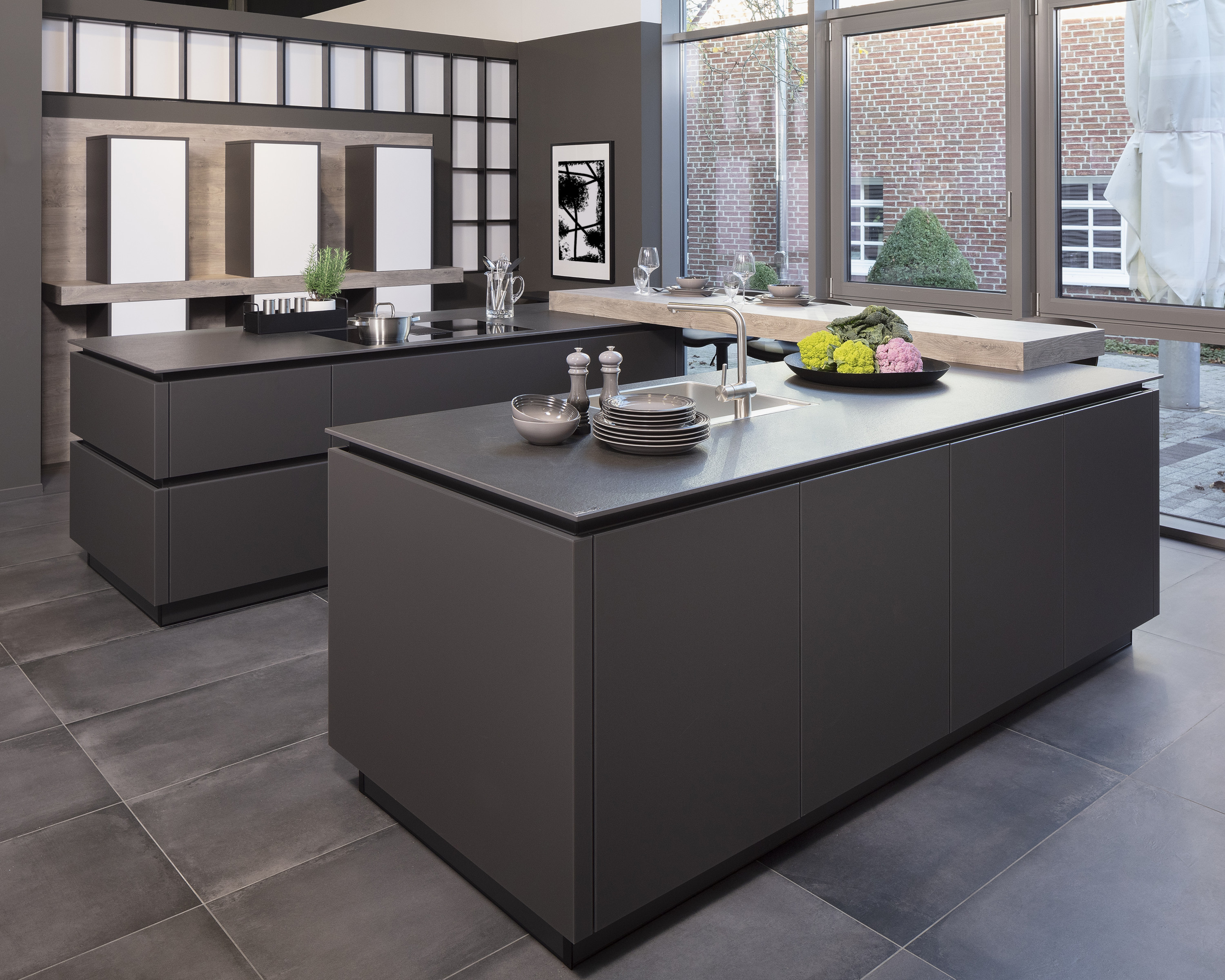 Moderne Küche mit dunklen Kücheninseln, großen Fenstern und stilvollen Accessoires.