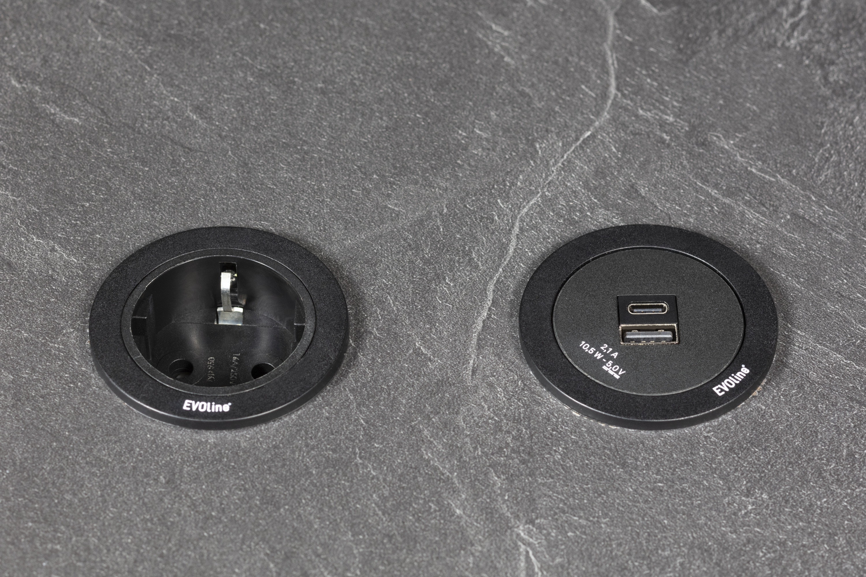 Runde Steckdose und USB-Anschluss in schwarzer Steinplatte eingelassen.